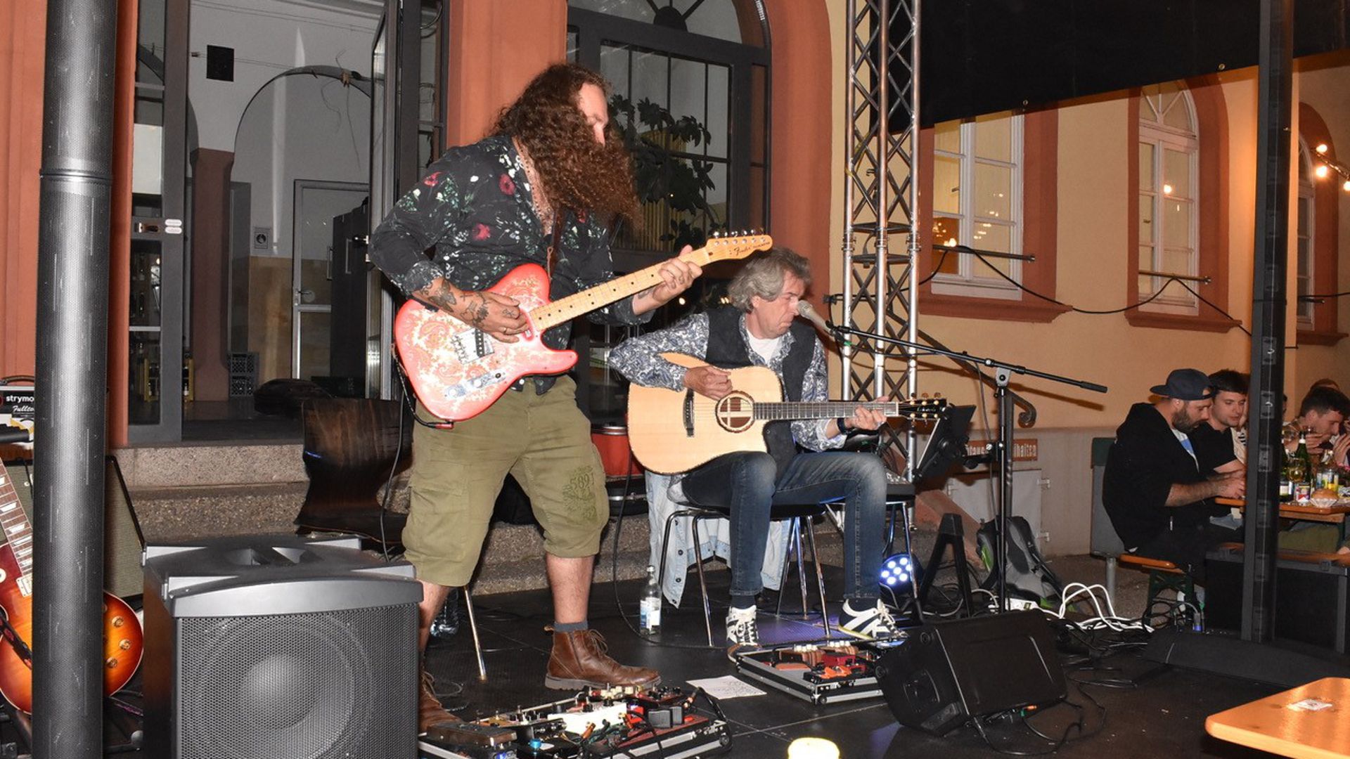 Irre Pickings auf der E-Gitarre präsentiert Sebastian Koehn (links) von Sunny-Wings vor der Alten Schule, daneben Reinhold Brommer. 