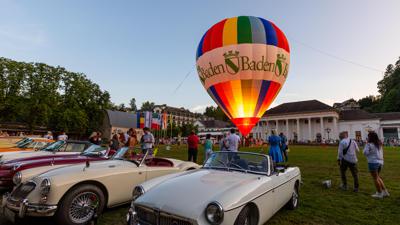 Erleuchteter Heißluftballon mit Baden-Baden-Aufschrift inmitten von Oldtimern auf der Kurhauswiese in Baden-Baden