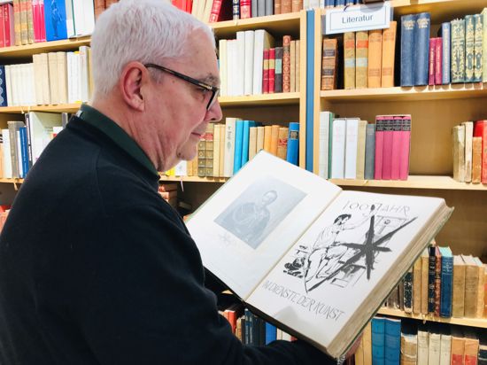 Christopher Pfleiderer blättert im Antiquariat im Baldreit in einem Exemplar. In den Regalen im Laden stehen rund 15.000 Bände.