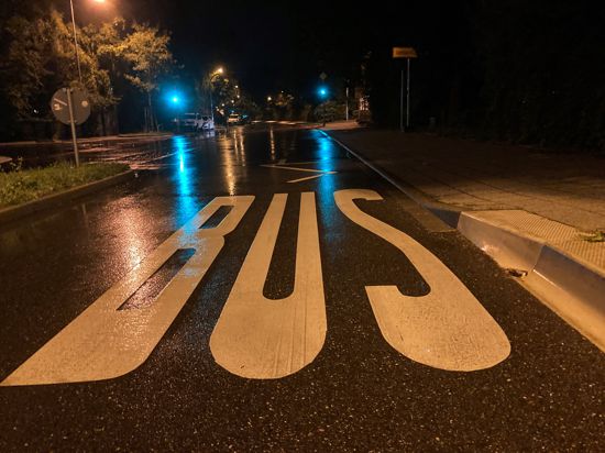 Schriftzug „Bus“ auf der regennassen Straße bei Nacht