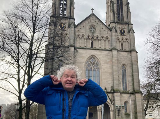 Heinz Faßbender steht vor der evangelischen Stadtkirche und hält sich die Ohren zu. 