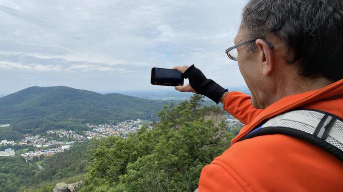 Hans Lange richtet sein Smartphone auf die Landschaft.