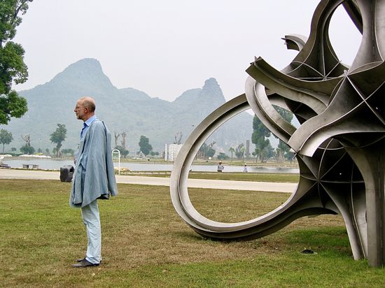 Eberhard Eckerle in der Landschaft von Guilin in China vor seiner Stahlskulptur „Strange Loops“ aus dem Jahr 2001