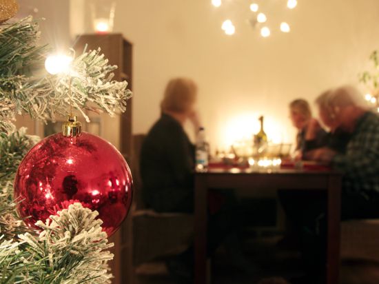 Familie sitzt an Heiligabend gemeinsam am Tisch und genießt das Weihnachtsessen.