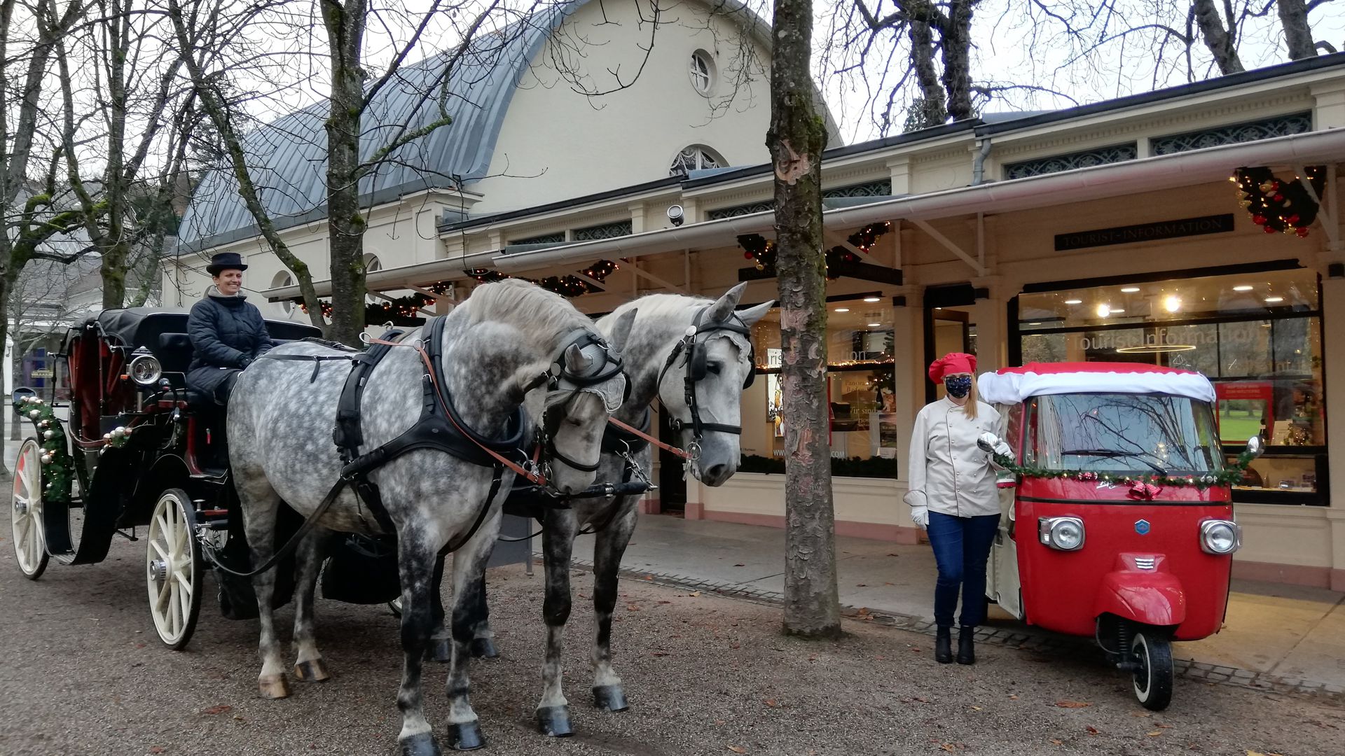 Eine Pferdekutsche und ein Tuk-Tuk stehen vor der Touristen-Information Baden-Baden.