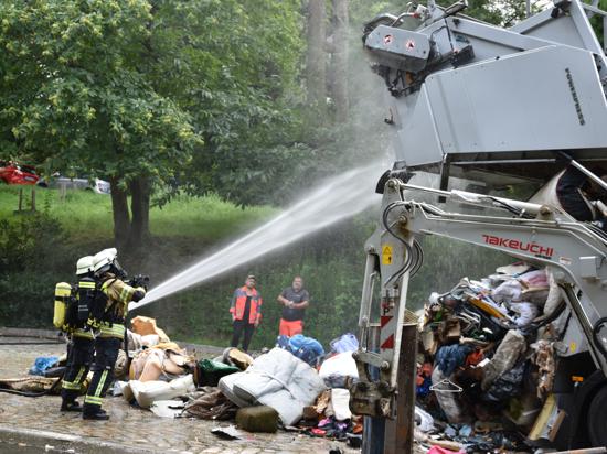 Feuerwehrleute löschen Sperrmüll in einem Müllfahrzeug.