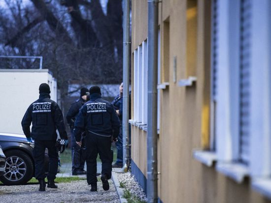 Polizeibeamte vor einem Wohnhaus, in dem eine Durchsuchung stattfindet.