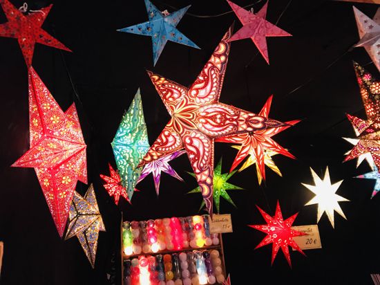 Leuchtende Weihnachtssterne hängen an einem Stand auf dem Weihnachtsmarkt in Baden-Baden.