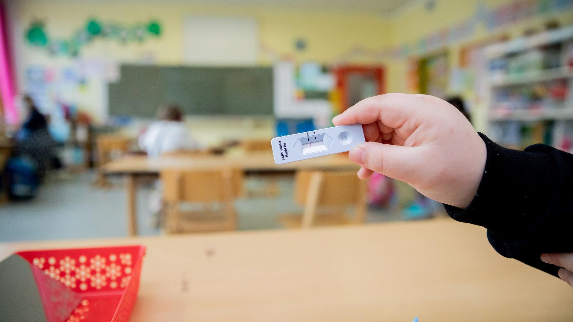 Ein Schüler hält bei einem Probelauf mit Corona-Schnelltests an einer Berliner Grundschule seinen negativen Test in die Kamera.