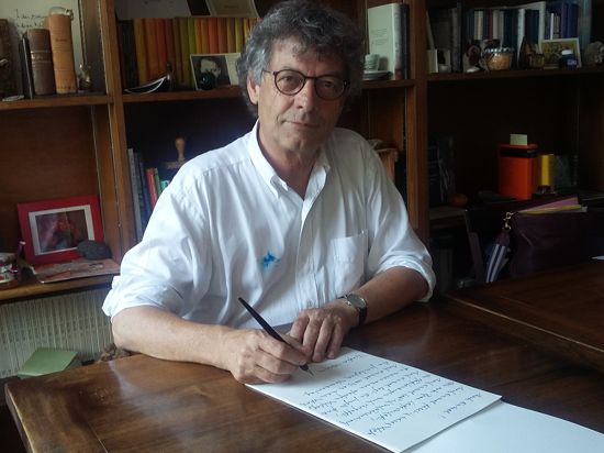 Ein Mann im weißen Hemd sitzt am Schreibtisch und schreibt