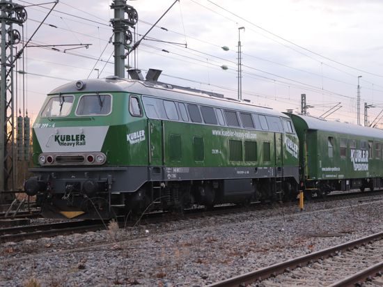 Zug  mit grüner Diesellok der Firma Kübler und einem Tragschnabelwagen