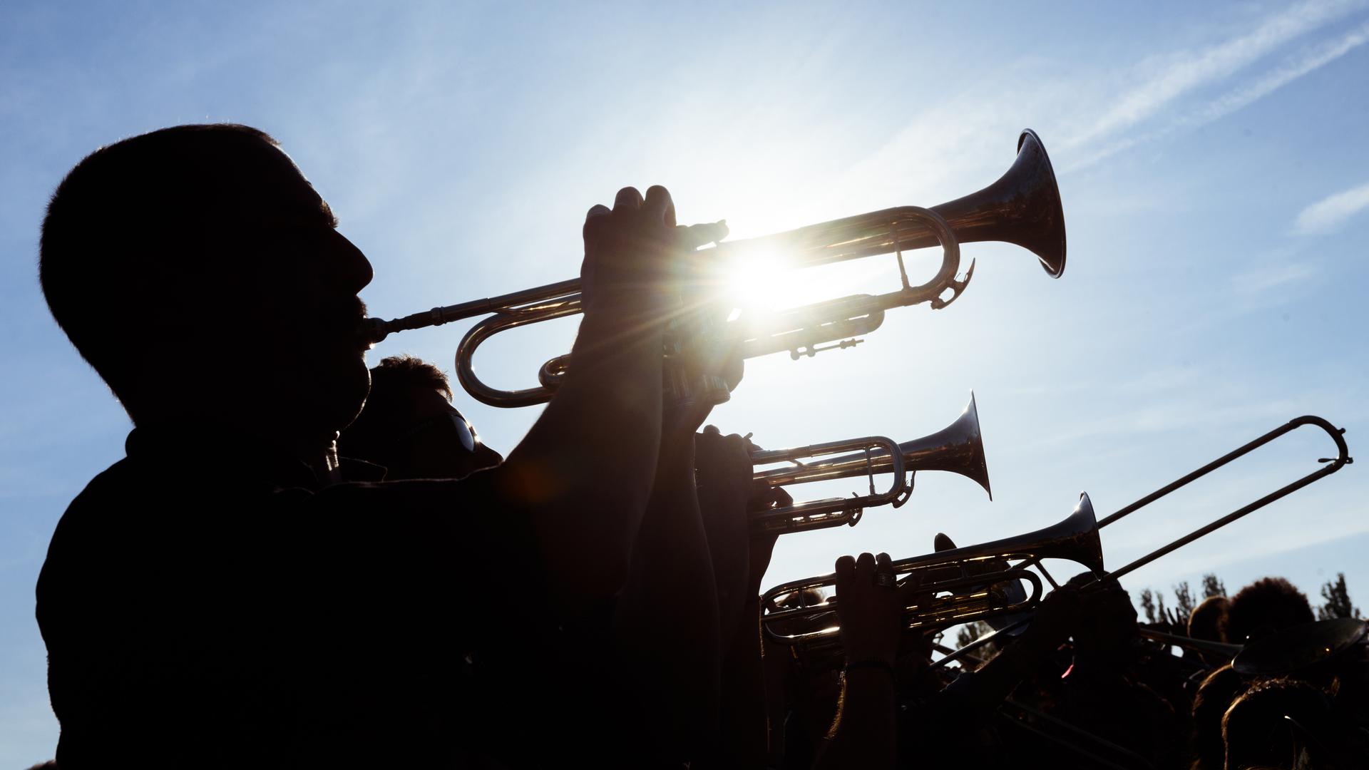 Eine Gruppe Musiker spielt bei strahlendem Sonnenschein Trompete und Posaunen.