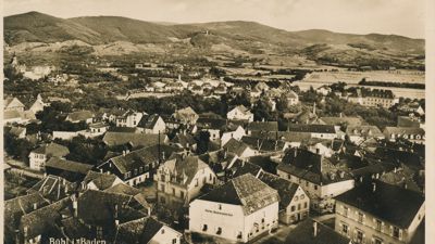 Das historische Bild zeigt den Blick über eine Stadt am Fuße von Bergen