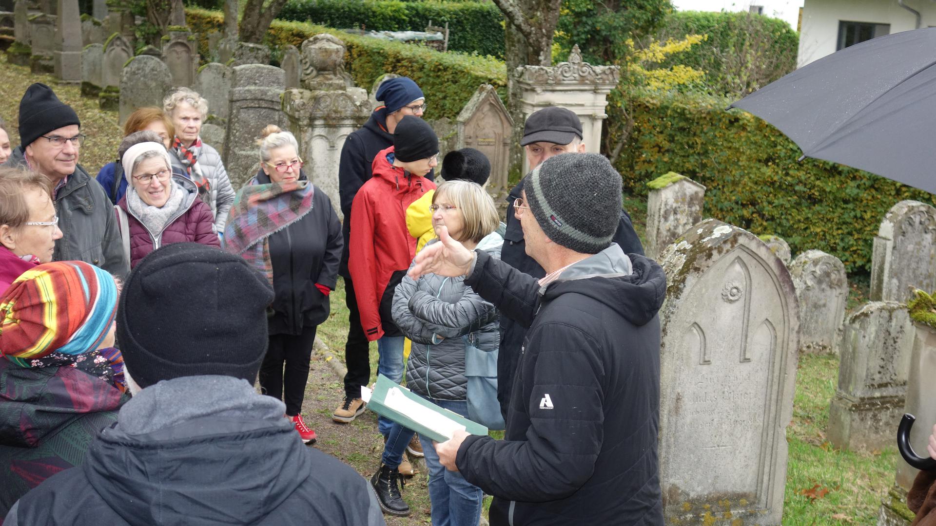 Stadtarchivar Michael Rumpf erläutert einer Besuchergruppe Stationen jüdischen Lebens auf dem jüdischen Friedhof in Bühl.