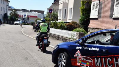 Ein angehender Motorradfahrer fährt vor dem Auto der Fahrschule Bernd Michel in Bühl