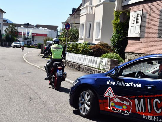 Ein angehender Motorradfahrer fährt vor dem Auto der Fahrschule Bernd Michel in Bühl