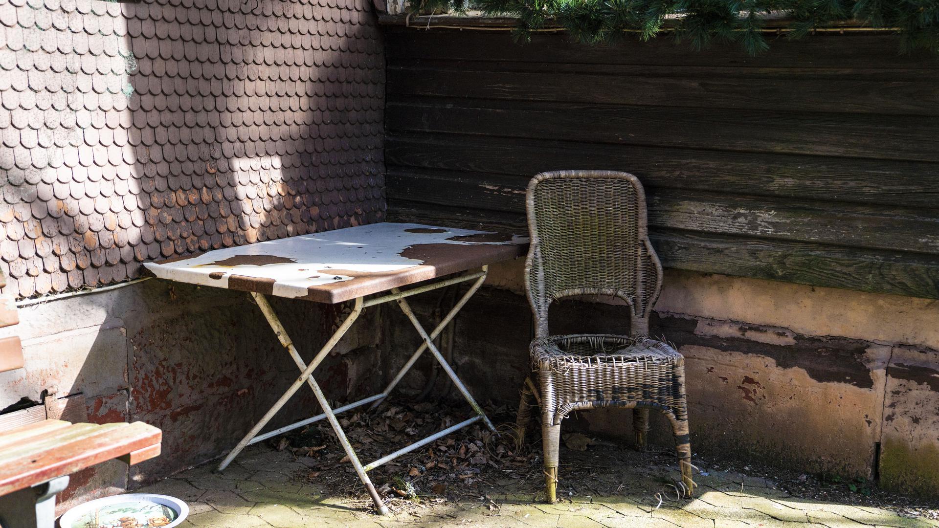 Ein kaputter Stuhl und ein maroder Tisch stehen vor dem Kurhaus Sand.
