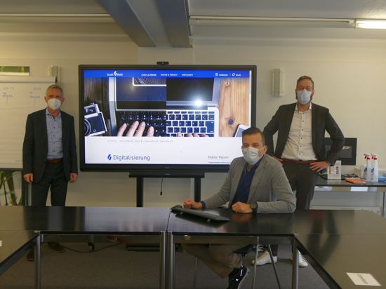 Drei Männer mit Masken vor Bildschirm