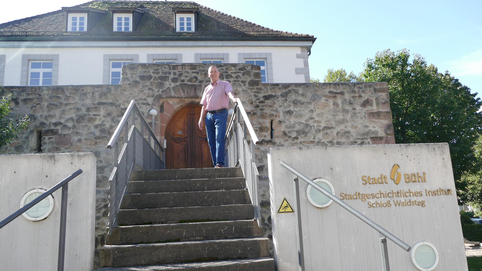 Ein Mann steht auf einer Treppe vor einem Haus