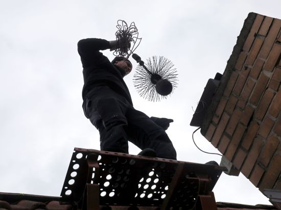 Ein Bezirksschornsteinfeger reinigt den Schornstein eines Wohnhauses.