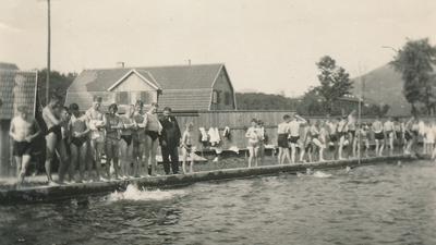 Auf einem alten Schwarz-Weiß-Bilder stehen Jugendliche und Kinder am Rand eines Schwimmbeckens. 