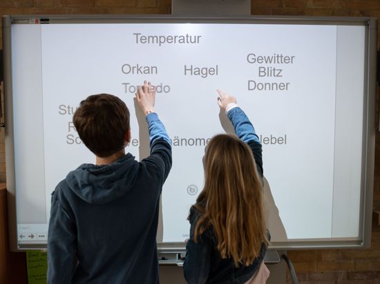 Ein Schüler und eine Schülerin arbeiten an einem Smartboard.