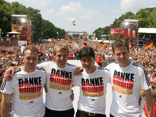 Sommermärchen 2006: Torwart-Trainer Andreas Köpke (von links), der damalige Bundestrainer Jürgen Klinsmann, sein damaliger Co-Trainer Joachim Löw und Team-Manager Oliver Bierhoff stehen auf der Fan-Meile am Brandenburger Tor in Berlin zusammen.