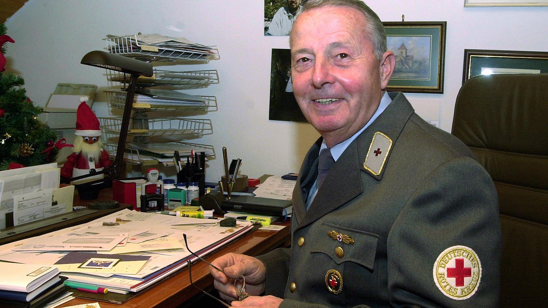 Werner Vögele sitzt in DRK-Uniform am Schreibtisch