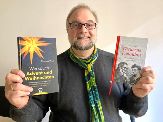 Der Autor Thomas Weiß zeigt zwei Bücher in die Kamera