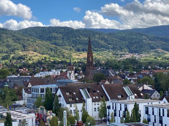 Blick vom Riesenrad des Bühler Zwetschgenfests auf die Dächer der Innenstadt mit dem Kirchturm der Pfarrei St. Peter und Paul sowie dem Schwarzwald. 