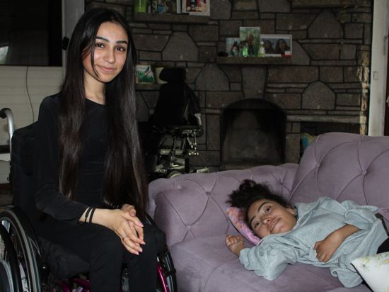 Nergiz Demir im Rollstuhl sitzend und Emine Demir auf dem Sofa liegend