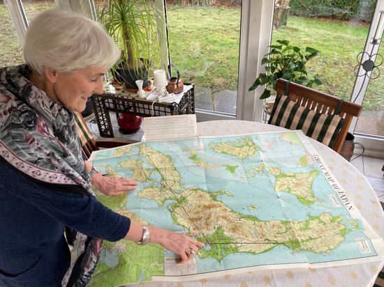 Brigitte Reith steht am Tisch. Darauf liegt eine große Karte, die Japan zeigt. 