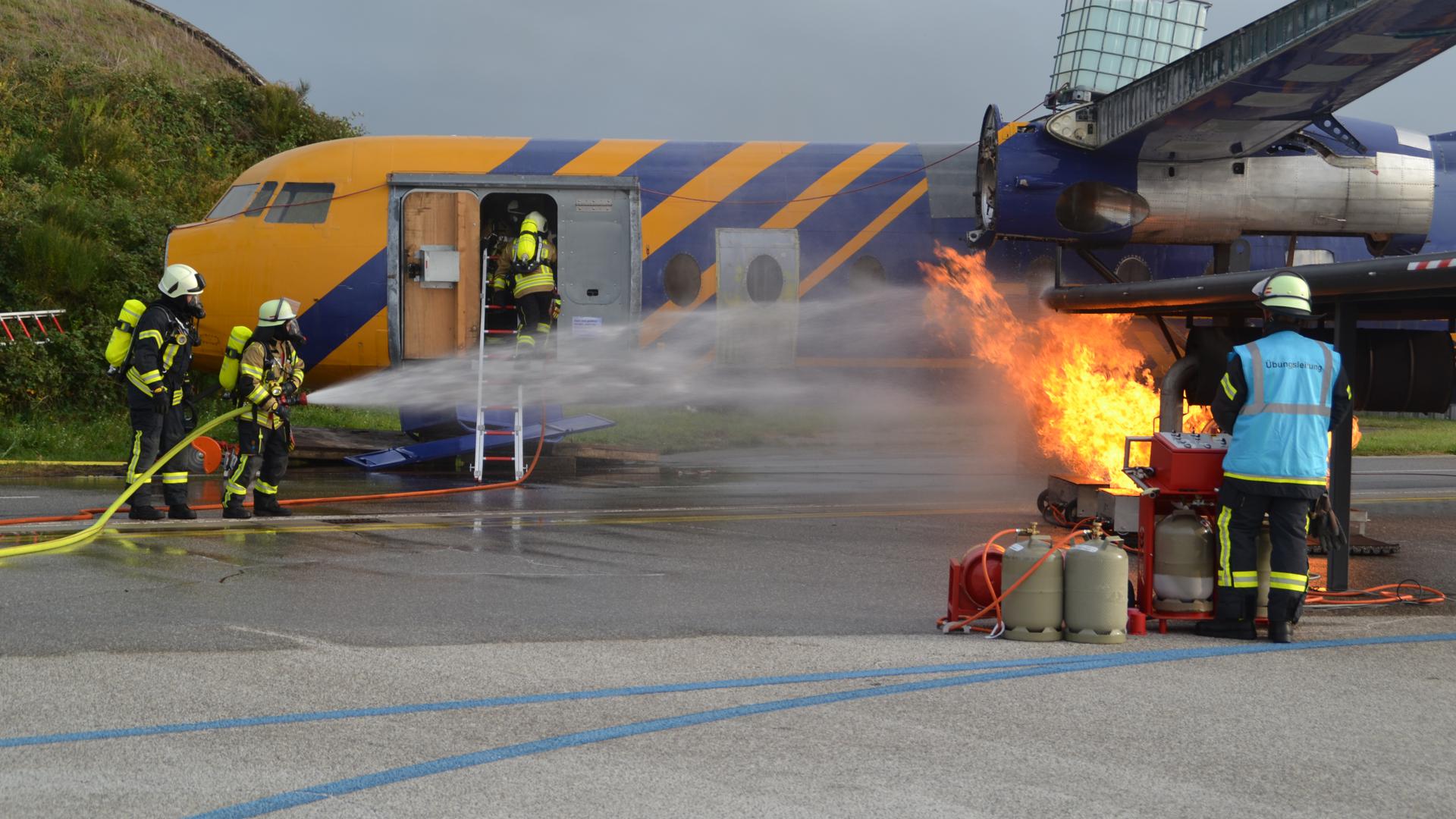 Mit Gasflaschen wird der Triebwerkbrand immer wieder angefacht, während die Flughafenfeuerwehr um die Brandbekämpfung und Passagierrettung bemüht ist.