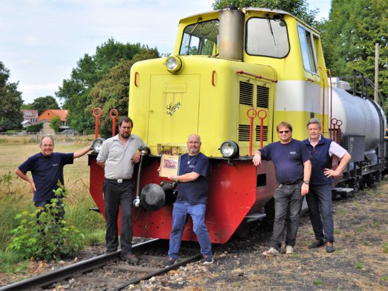 Fünf Männer stehen vor einer gelben Diesellok
