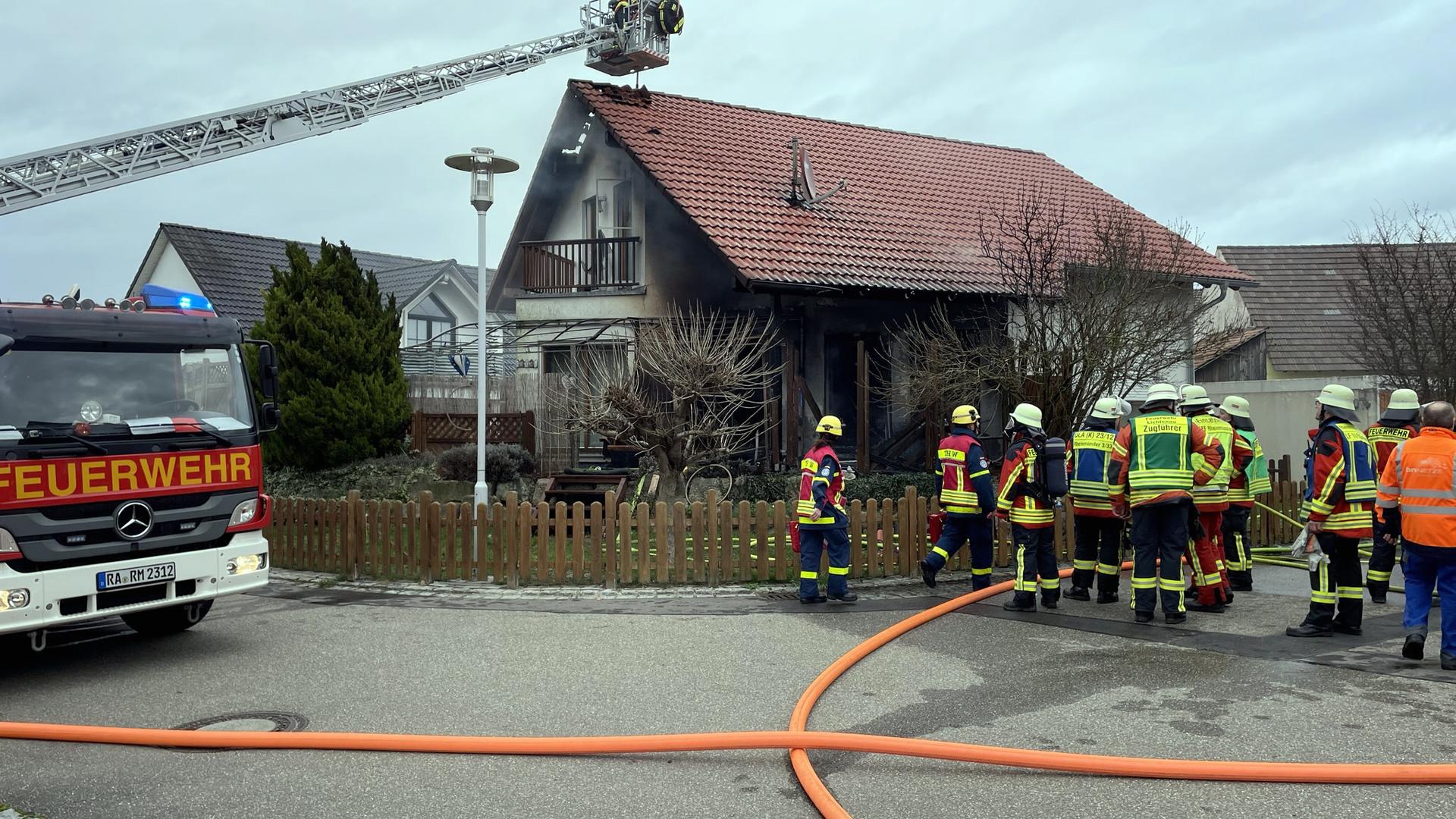 Brand in Rheinmünster in der Straße „Am Kanalbach“. Feuerwehrleute auf der Straße vor dem Haus sowie im Korb der Drehleiter über dem rußigen Haus.