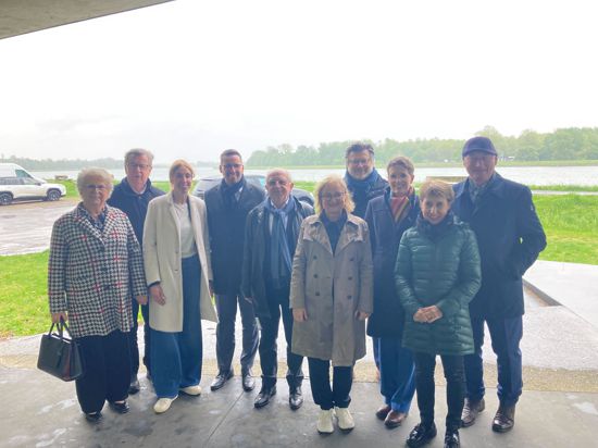 Politiker und Politikerinnen stehen am verregneten Rhein in Drusenheim.
