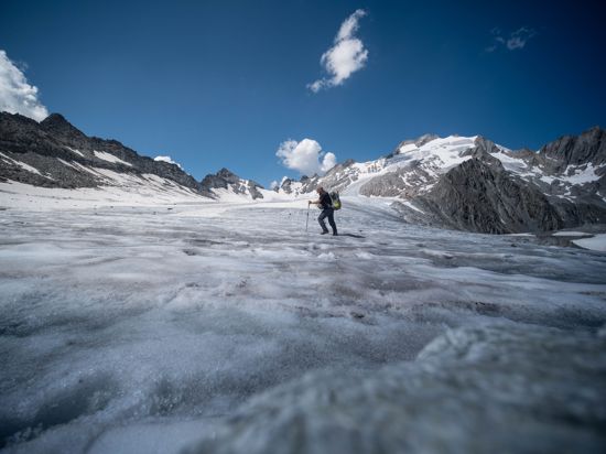 Ein Mann läuft unter blauem Himmel über ein Gletscherfeld.
