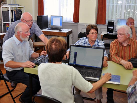 Senioren in einer Gruppe an Tischen mit Computern