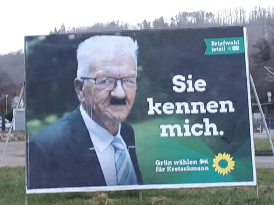Landtagswahlkampf-Plakat der Grünen, auf dem Winfried Kretschmann mit einem aufgemalten Hitlerbart zu sehen ist.