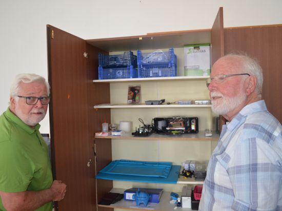 Zwei Männer vor einem geöffneten Schrank mit Ersatzteilen