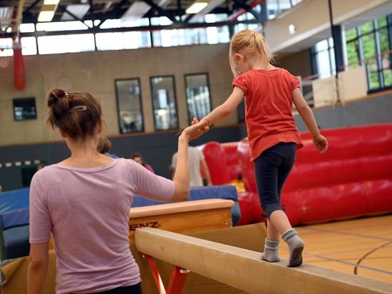 Eltern und Kinder turnen beim Vereinssport in einer Sporthalle in Berlin.