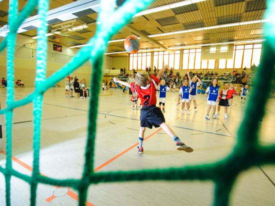 Blick von hinten durch das Netz eines Handballtores auf junge Handballspieler.