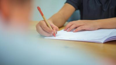 Ein Grundschüler sitzt an einem Tisch und schreibt mit einem Kugelschreiber in sein Heft. (zu dpa «Was Hänschen nicht lernt - Viertklässler immer schwächer») +++ dpa-Bildfunk +++