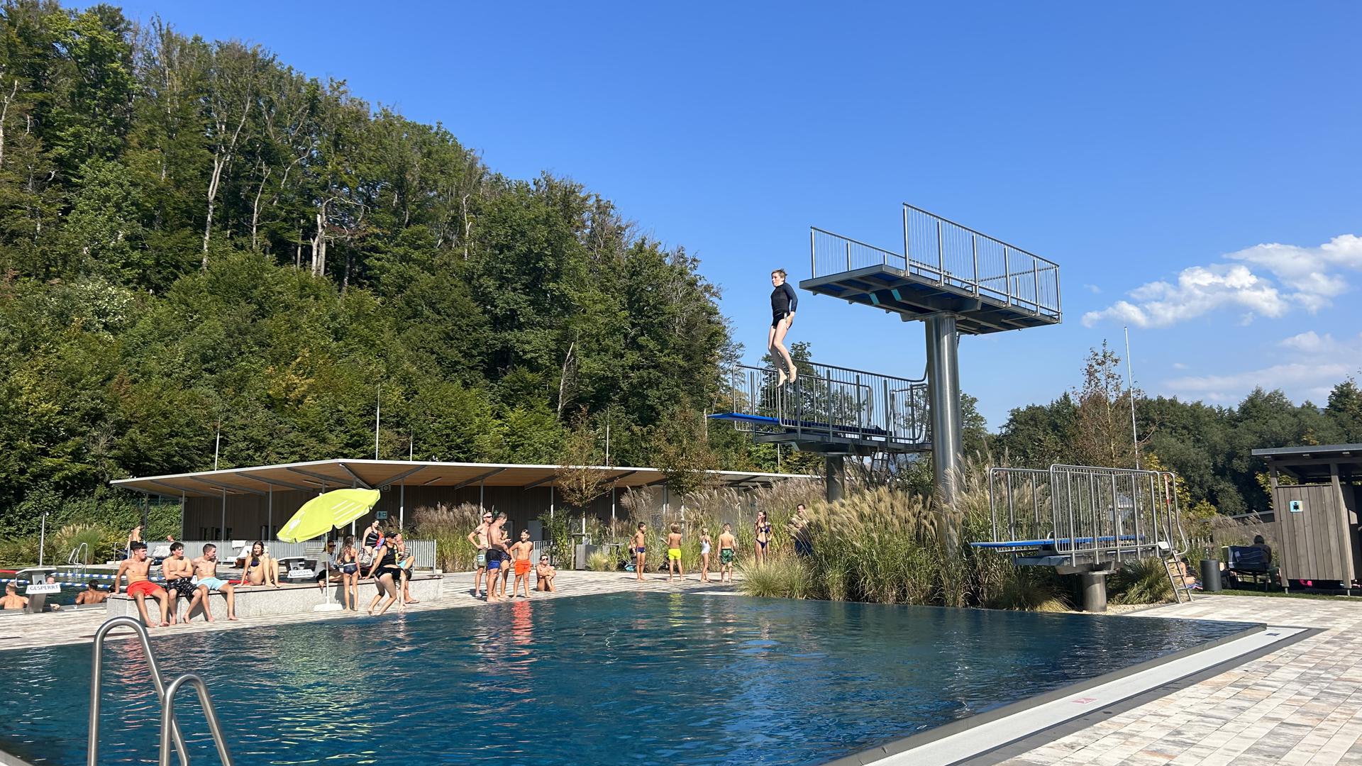 Ein Mensch springt von einem Turm in ein Schwimmbecken.