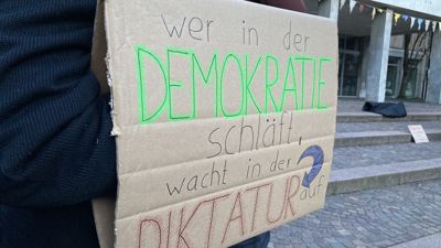 ein Protestplakat mit der Aufschrift „Wer in der Demokratie schläft, wacht in der Diktatur auf“