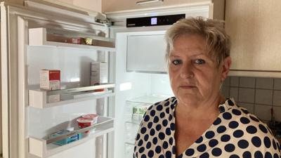 eine Frau steht mit verärgertem Gesicht vor einem geöffneten Kühlschrank