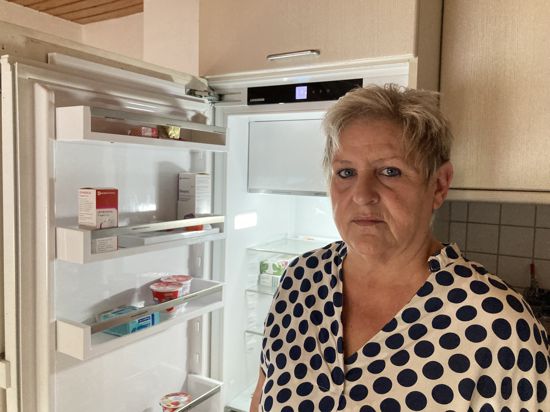 eine Frau steht mit verärgertem Gesicht vor einem geöffneten Kühlschrank