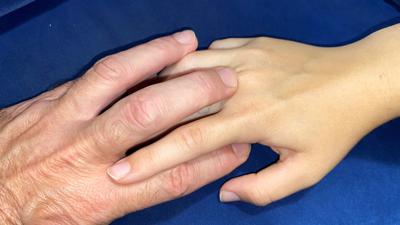 Die Hand eines älteren Mannes und einer jungen Frau berühren sich.