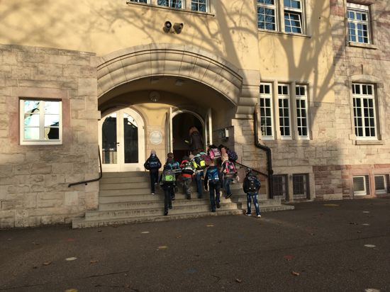 Vor dem Eingang der Hans-Thoma-Schule steht eine Gruppe von Schülern 