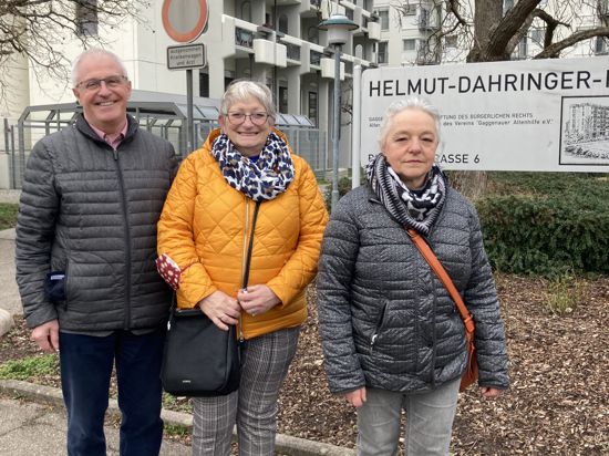 Ein Mann und zwei Frauen stehen vor einem Hochhaus und einem Schild, auf dem Helmut-Dahringer-Haus geschrieben steht.